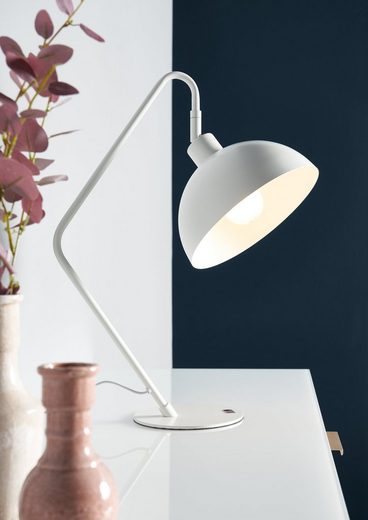 Moderne weiße Schreibtischlampe auf weißer Oberfläche Weiße Schreibtischlampe mit gebogenem Arm, neben rosa Vase und Trockenblumen, seitlich fotografiert