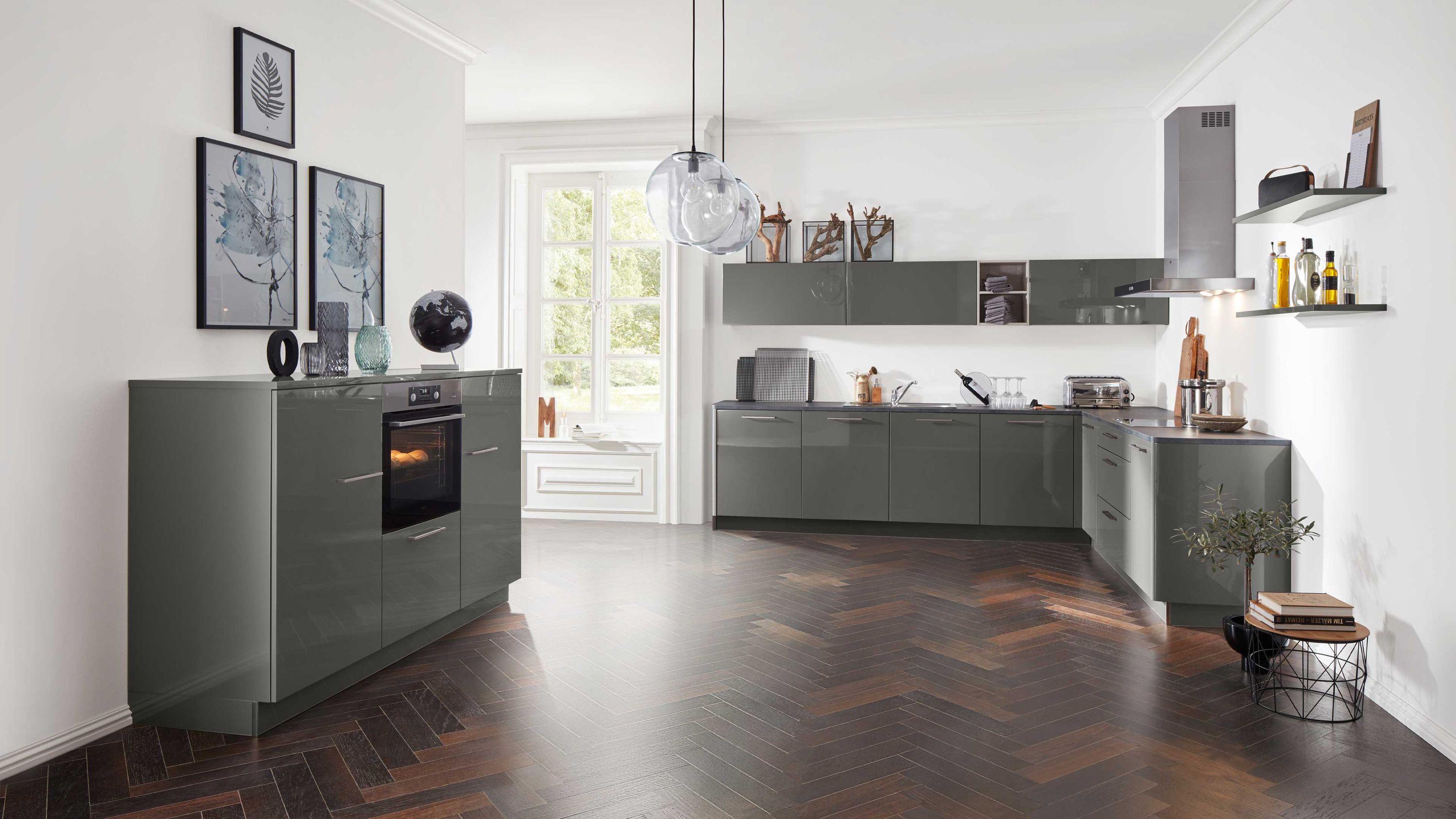 Elegante Küche mit dunklen Fronten und Fischgrätboden Küche mit grauen Schränken Einbauofen Fischgrätboden Hängelampen und offenem Regal bei Tageslicht