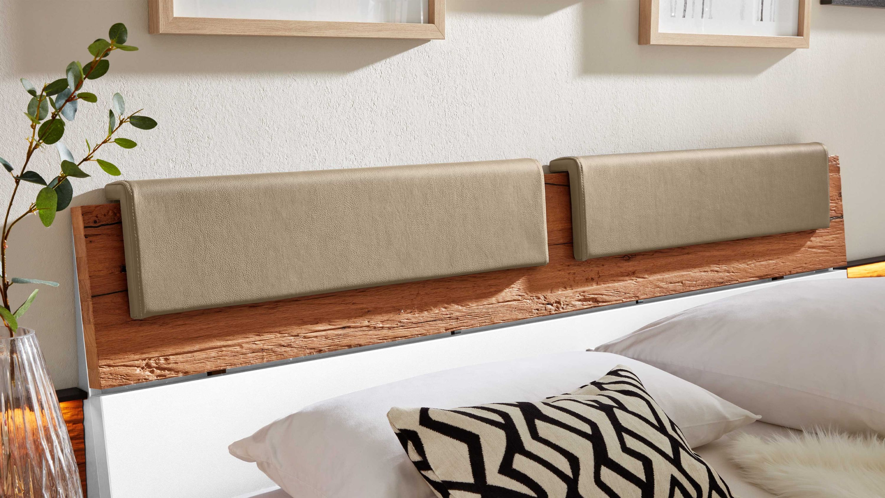 Holz-Kopfteil mit zwei rechteckigen taupefarbenen Polstern aus Kunstleder an einem Bett
