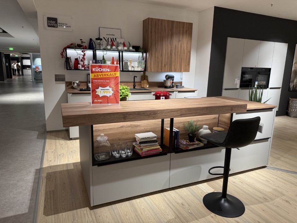 Moderne Küche mit zentraler Insel, Holzarbeitsplatte und offenen Regalen, dahinter Schränke mit Holzfronten