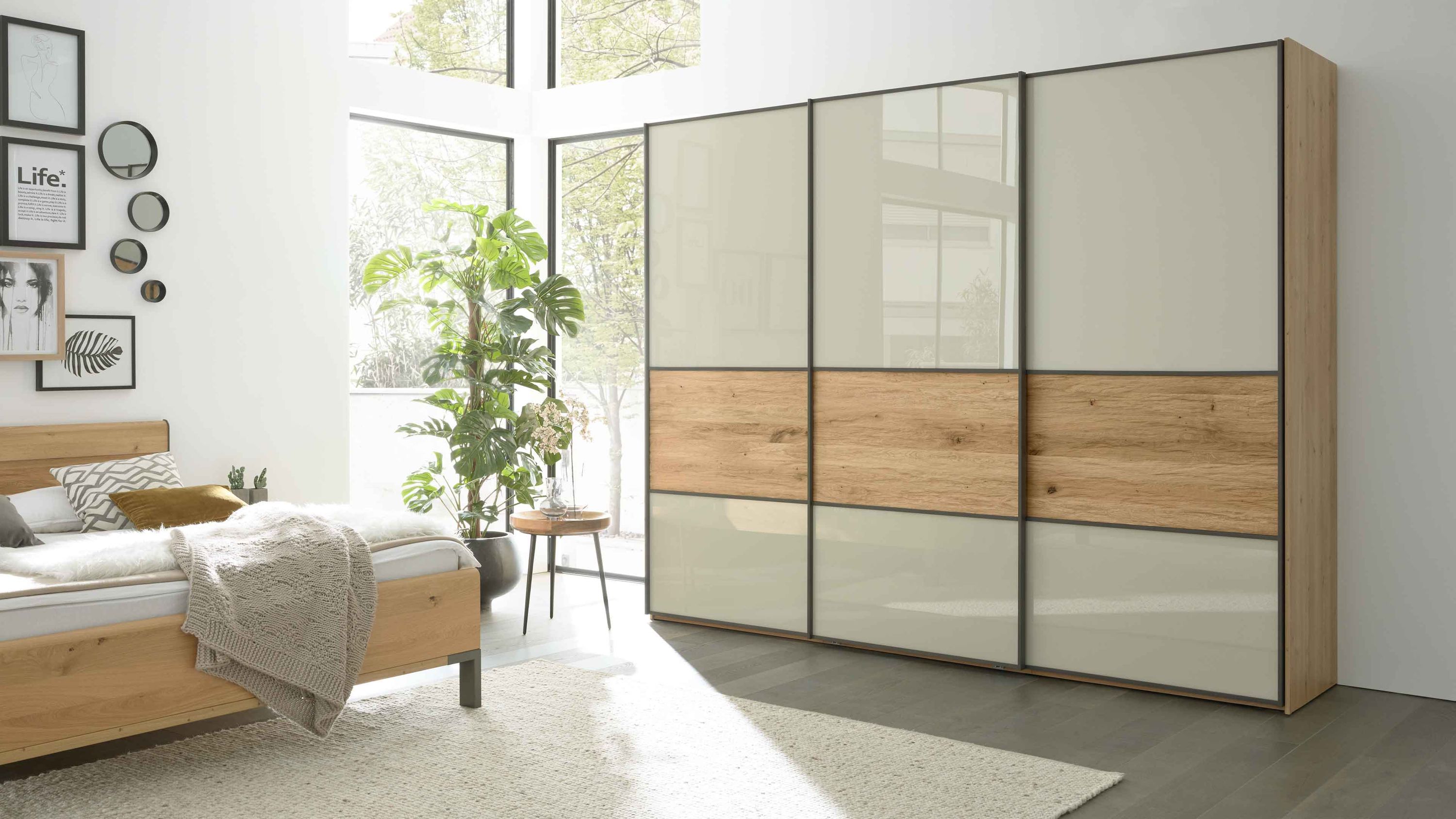 Dreiteiliger Schwebetürenschrank mit hellen Türen und mittleren Holzpaneelen in einem Schlafzimmer