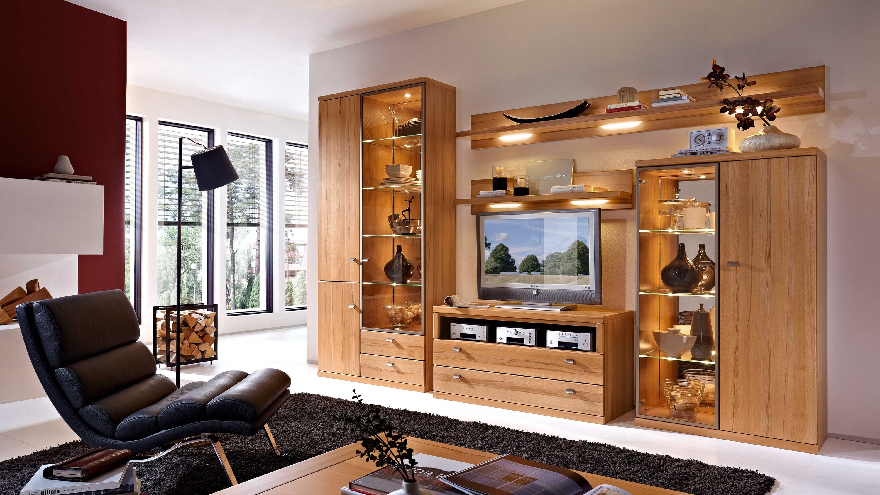 Wohnwand aus hellem Holz mit Vitrinenschränken Regalen und TV-Board in modernem Wohnzimmer