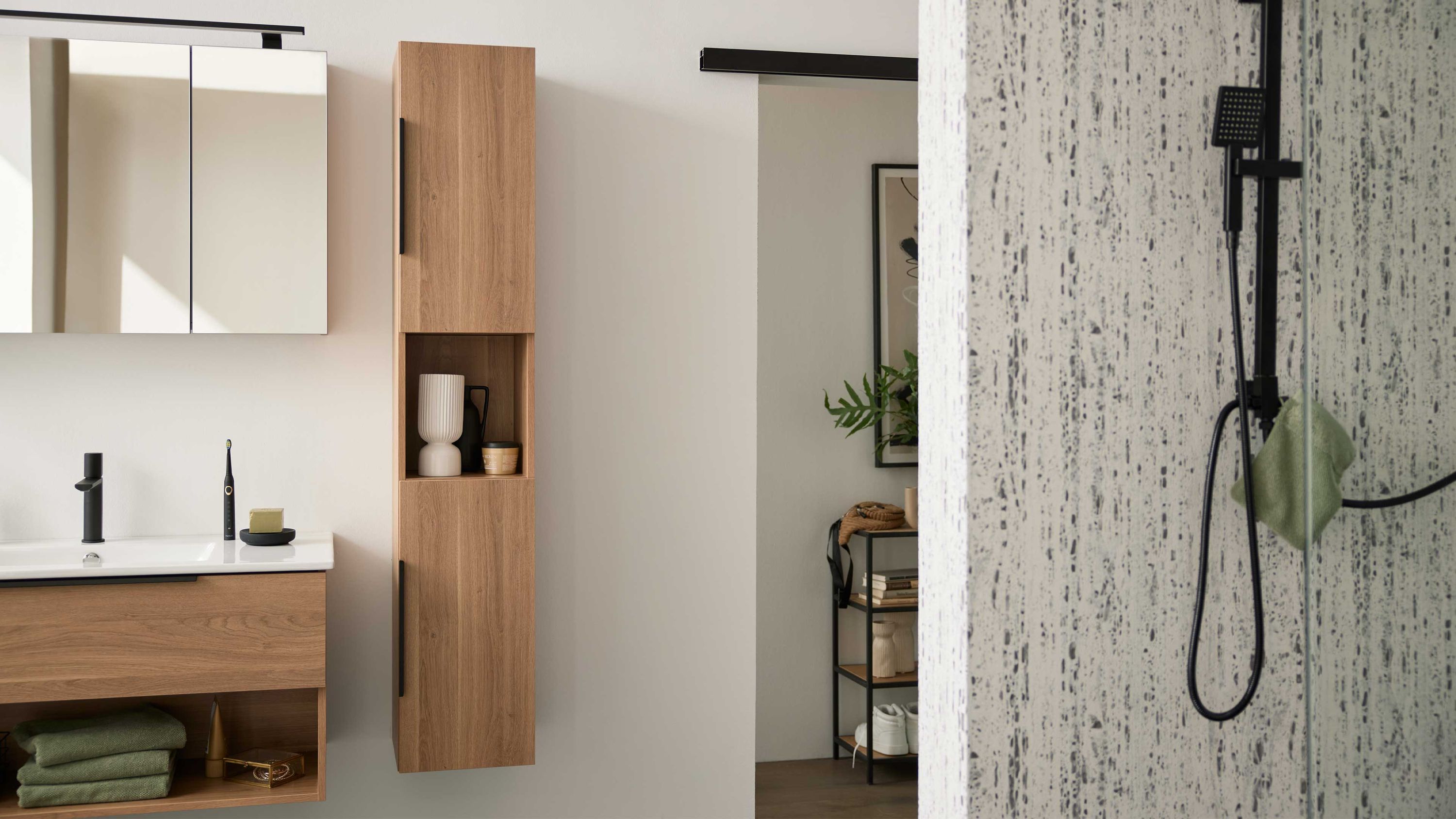 Hochschrank mit zwei Türen in brauner Holzoptik Hochschrank mit zwei Türen und offenem Fach in brauner Holzoptik an weißer Wand im Badezimmer