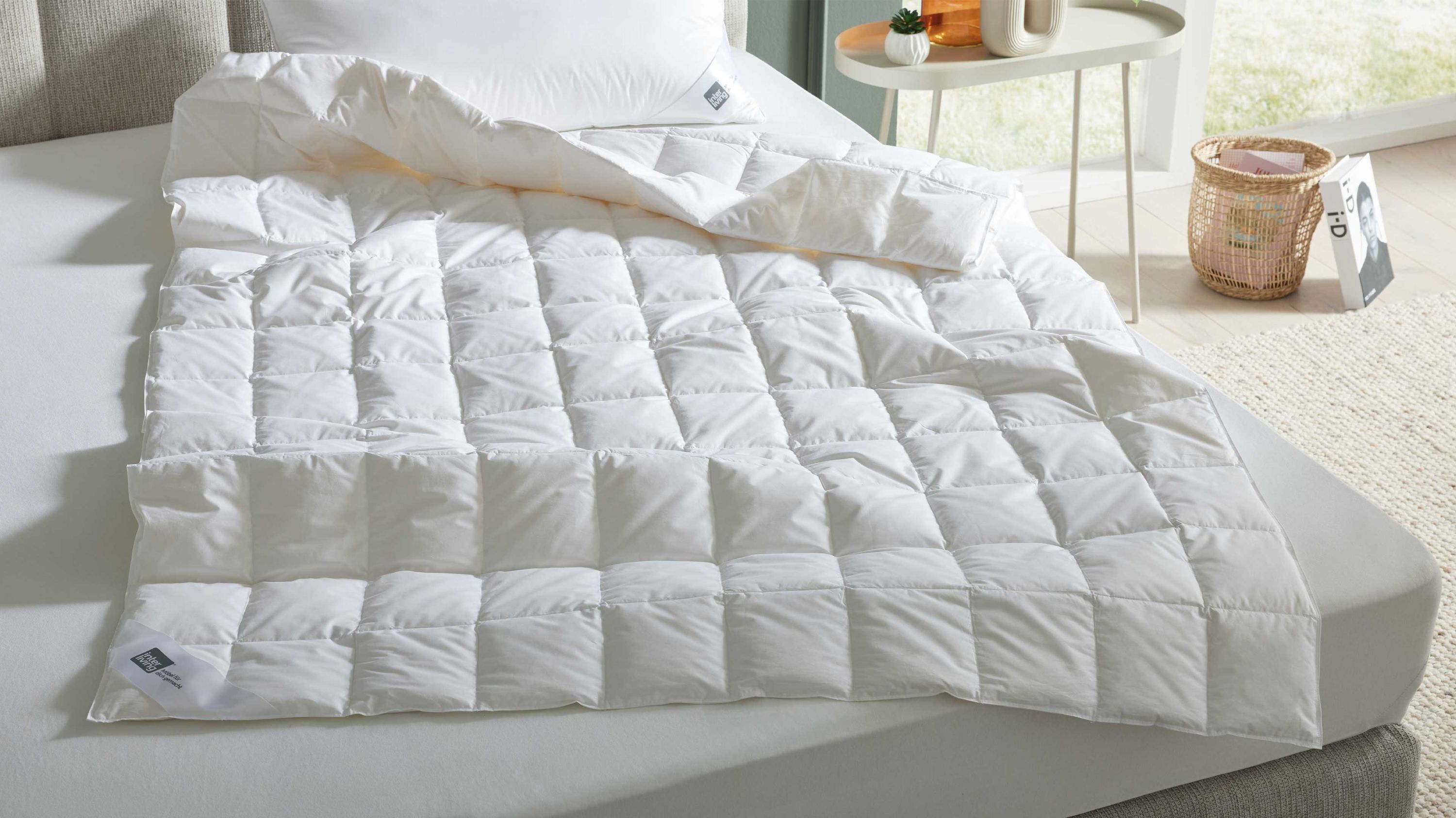 Weiße Steppbettdecke mit quadratischem Muster auf einem Bett mit weißem Bettlaken