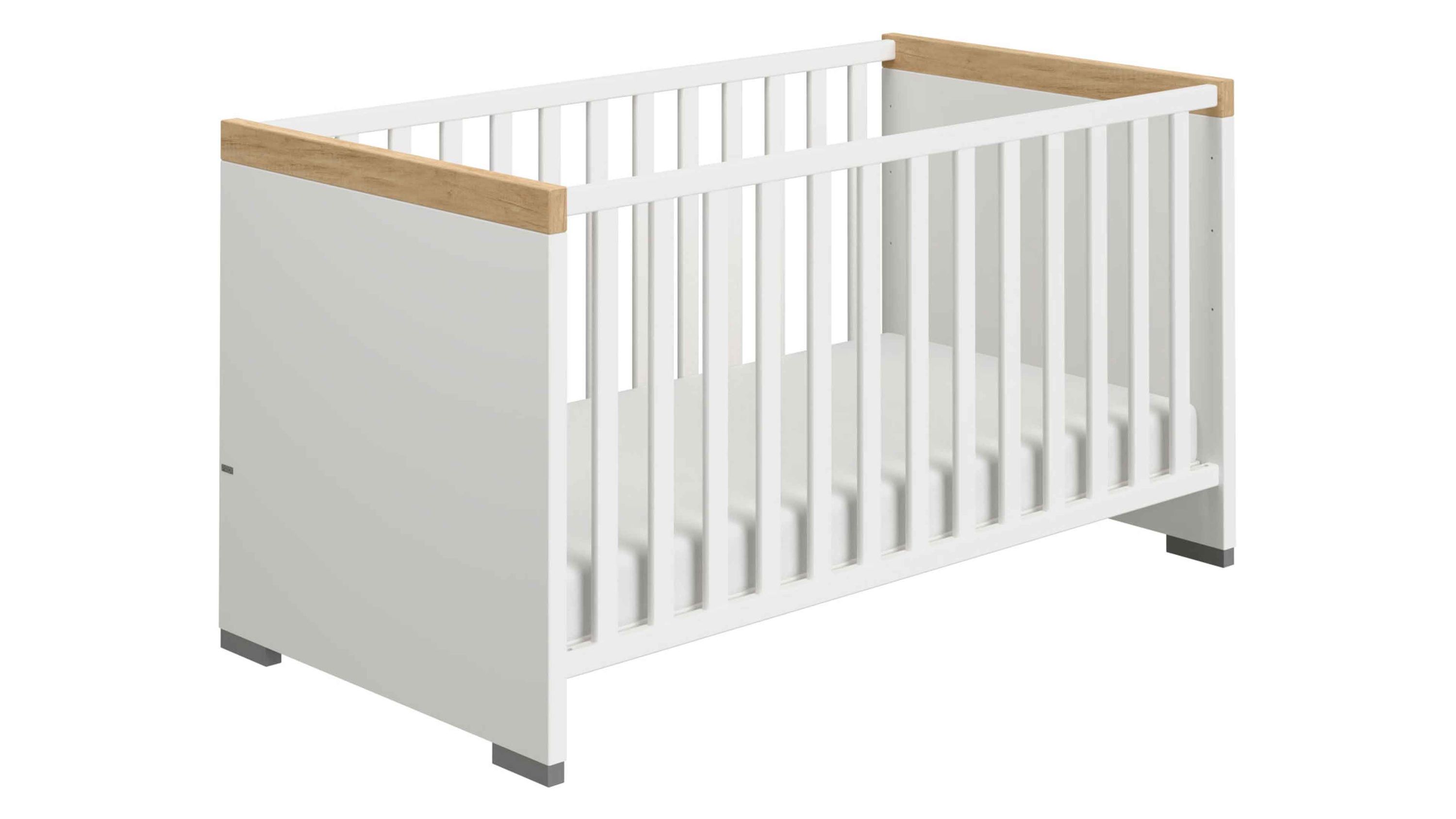 Weißes Babybett mit Gitterstäben und hellbraunen Holzabschlüssen an den Kopfenden