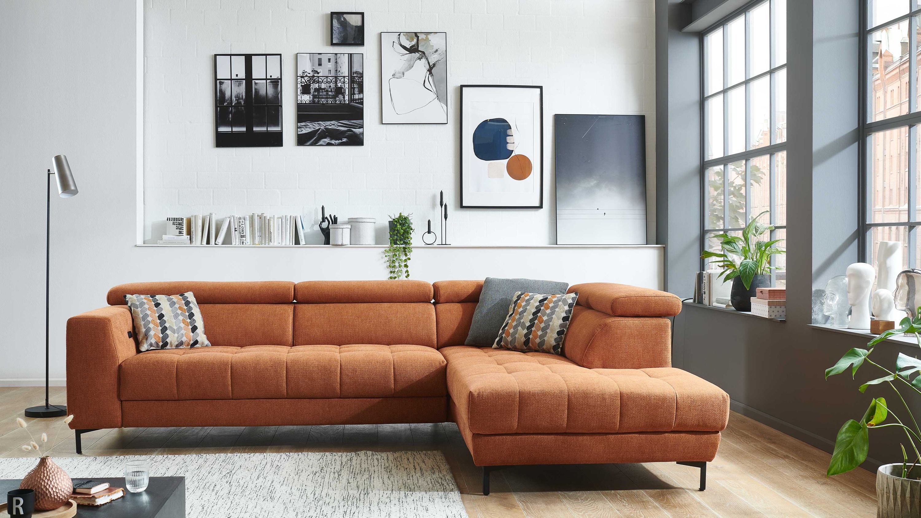 Ecksofa mit oranger Strukturstoffbezug und schwarzen Metallfüßen in modernem Wohnzimmer mit großen Fenstern